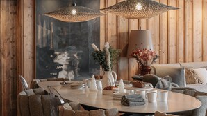 Un espace repas comprenant une table ronde, plusieurs chaises et deux lampes suspendues.
