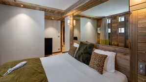 A bedroom with a large bed, wooden headboard, and a mirror.