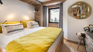 A bedroom with a bed, a wooden headboard, a window with a view, and a decorative wall piece.
