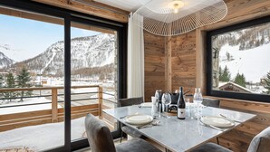 A dining area with a table set for four, large windows offering a view of snowy mountains, and a modern pendant light.