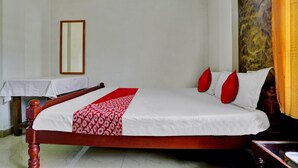 Una cama bien hecha con colcha roja y blanca, cabecera de madera y almohadas rojas.
