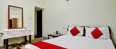 A hotel room with a bed, a nightstand, a mirror, and a table with a white tablecloth.