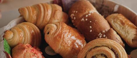 Une variété de viennoiseries, notamment des croissants et un rouleau au chocolat, disposés sur un plateau.