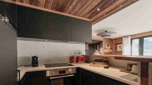 Una cocina moderna con armarios oscuros, un horno Bosch, una estufa integrada y vigas de madera en el techo.