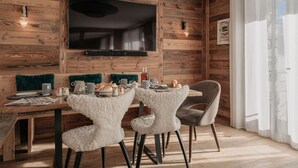 Un comedor con pared de madera, televisor de pantalla plana y una mesa dispuesta para dos personas.