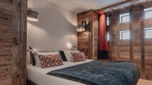 Un dormitorio con una cama grande, paredes de madera, una ventana con cortinas y una lámpara colgante.