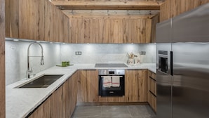 A modern kitchen with wooden cabinetry, a stainless steel refrigerator, a Bosch oven, and a sink with a modern faucet.