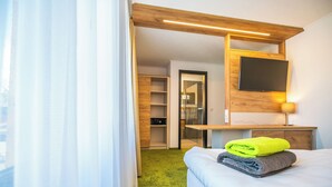 Une chambre d’hôtel équipée d’un lit, d’un bureau, d’une télévision et d’un espace douche.