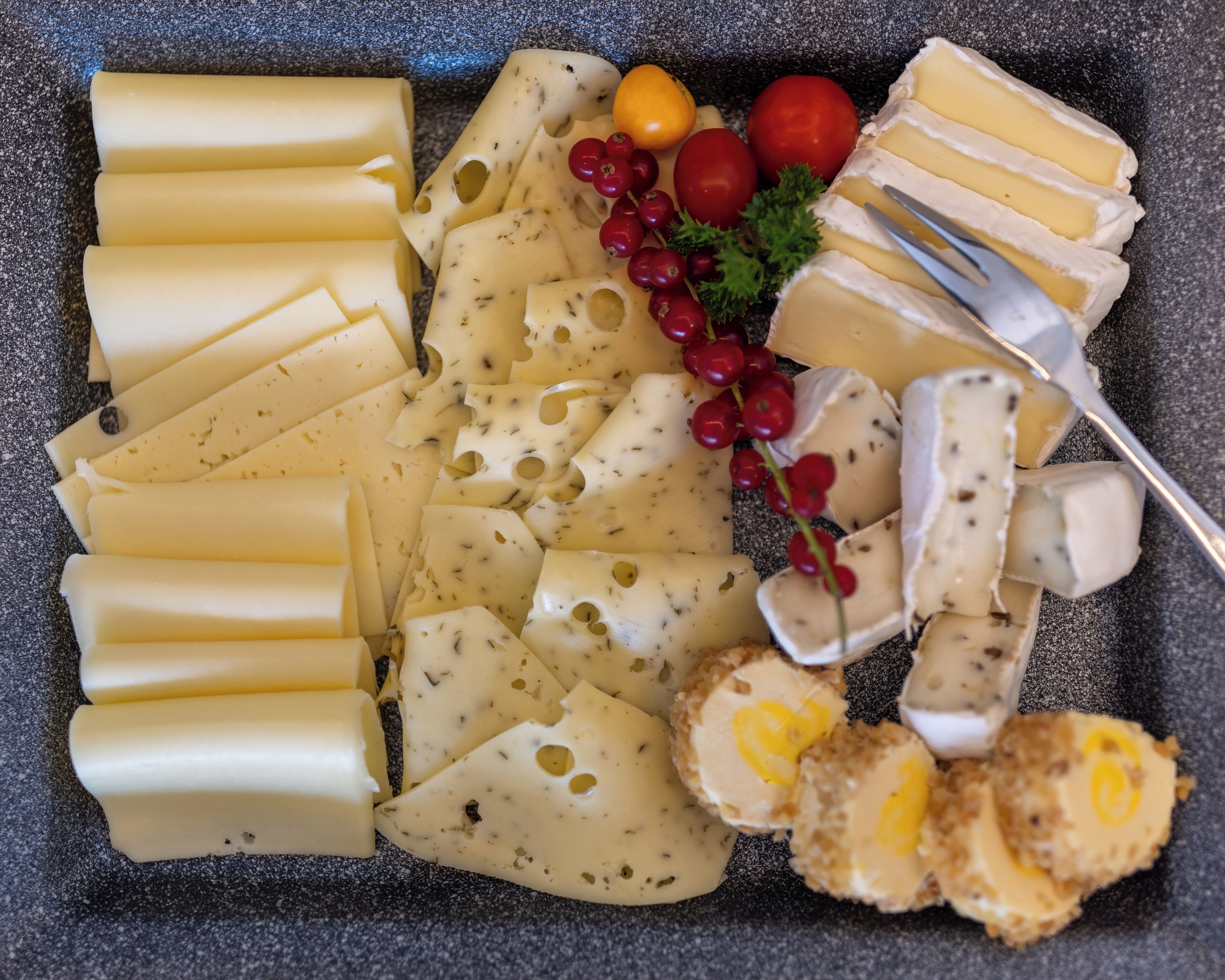 Variedad de quesos y frutas sobre una tabla de pizarra.