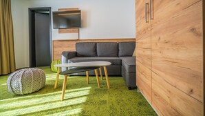 Un salon moderne avec un canapé gris, une petite table ronde et un tapis vert.