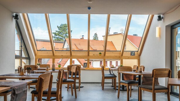 Un restaurant doté d’un plafond haut et de grandes fenêtres, offrant une vue sur les bâtiments environnants.