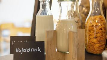 A display of milk bottles and a jar of cereal on a wooden counter with a sign reading "Haferdrink".
