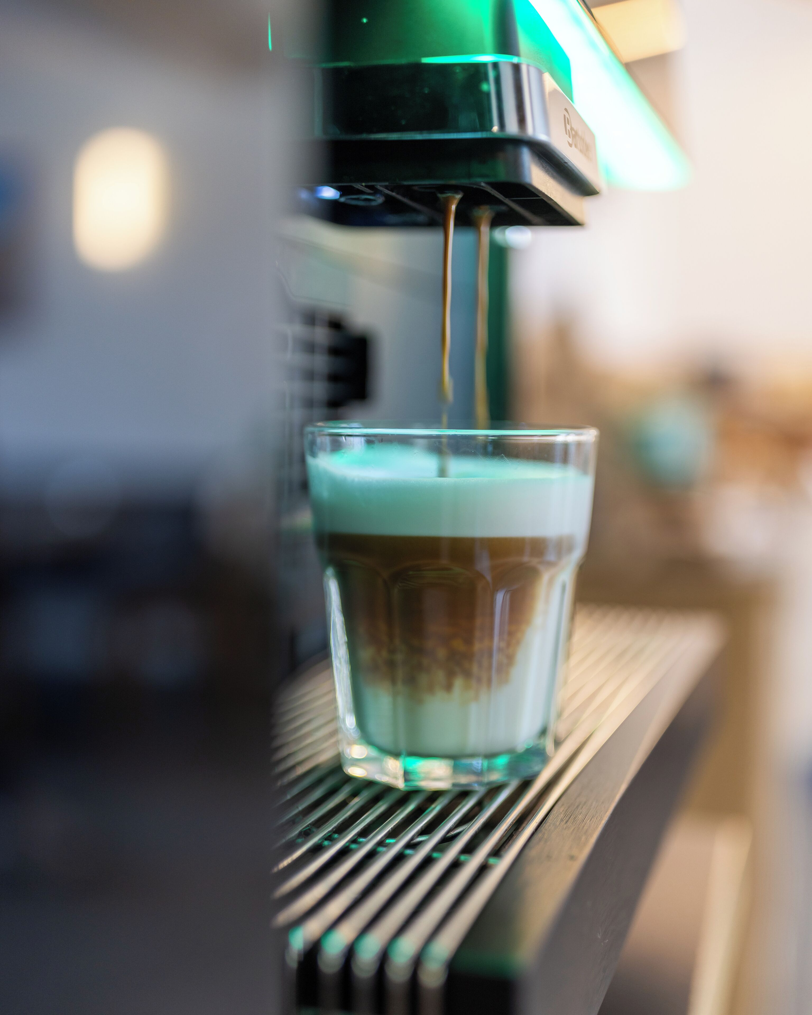 A close-up of a coffee machine dispensing coffee into a glass cup.