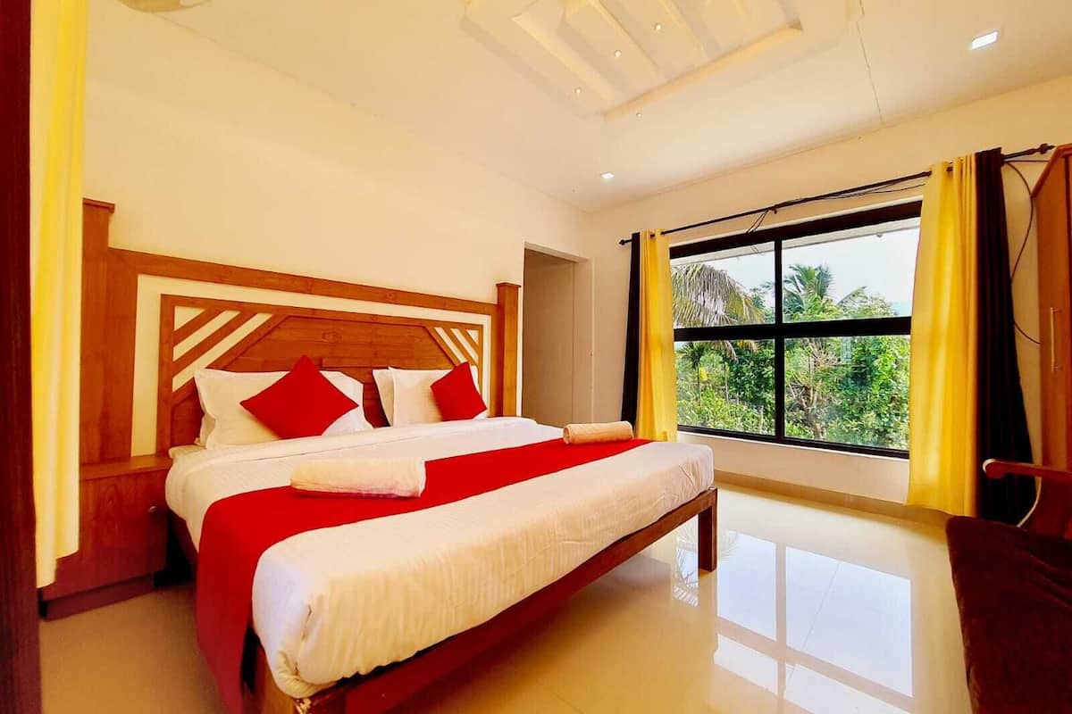 A hotel room with a large bed, wooden headboard, and a view of greenery through a large window.
