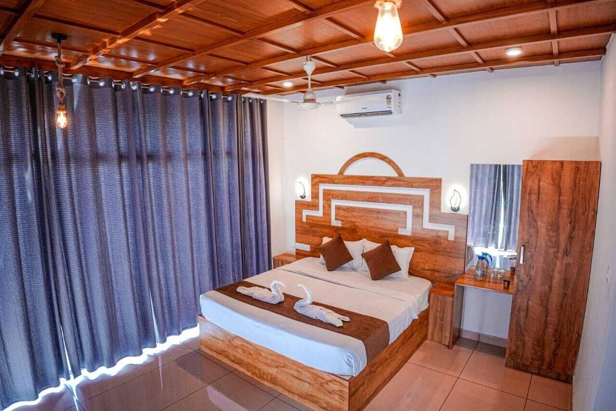 A hotel room with a wooden headboard, a bed with white linens, a nightstand, and a mirror.