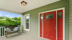A porch with a red door, a bench with cushions, and a light fixture above. - A peaceful retreat just off the Seneca Lake Wine Trail—close to 20+ wineries and Smith Park’s lakeside fun. (Hector)