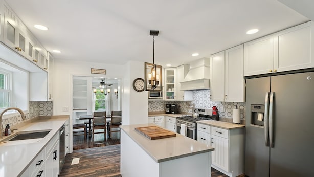A modern kitchen with white cabinetry, a central island, stainless steel appliances, and a patterned backsplash. - A peaceful retreat just off the Seneca Lake Wine Trail—close to 20+ wineries and Smith Park’s lakeside fun. (Hector)