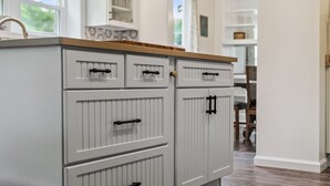 A kitchen with white cabinetry, a wooden countertop, and a clock on the wall. - A peaceful retreat just off the Seneca Lake Wine Trail—close to 20+ wineries and Smith Park’s lakeside fun. (Hector)