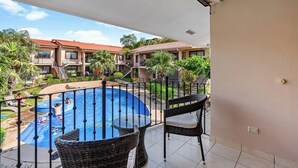 A balcony with a view of a swimming pool, lounge chairs, and a table. - Green Turtle 20 in Coco is an elegantly appointed 2-bedroom, 1-bath condo with a swimming pool located within a 7-minute walk of the beach. <br><br>📢Important announcement: Golf cart with condo available upon request for additional charges (Playas Del Coco)
