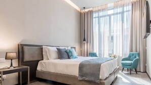 Ein modernes Hotelzimmer mit einem großen Bett, einem Nachttisch, einer Lampe und einem Sessel.
