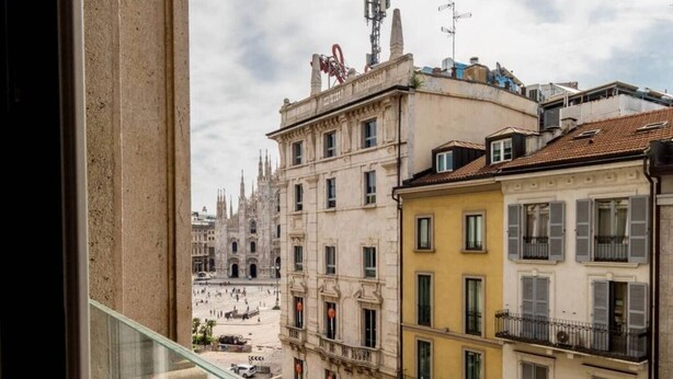 Blick aus einem Fenster auf einen historischen Platz mit einem markanten Dom im Hintergrund.