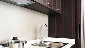 Eine moderne Küche mit dunklen Holzschränken, einer Edelstahlspüle und einer schwarzen Induktionskochplatte.