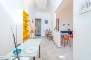 A hallway with a yellow bookshelf, a table with a fan, and a clock on the wall. - Room 'Al 214 - Suite' with Balcony, Wi-Fi and Air Conditioning (Ragusa)