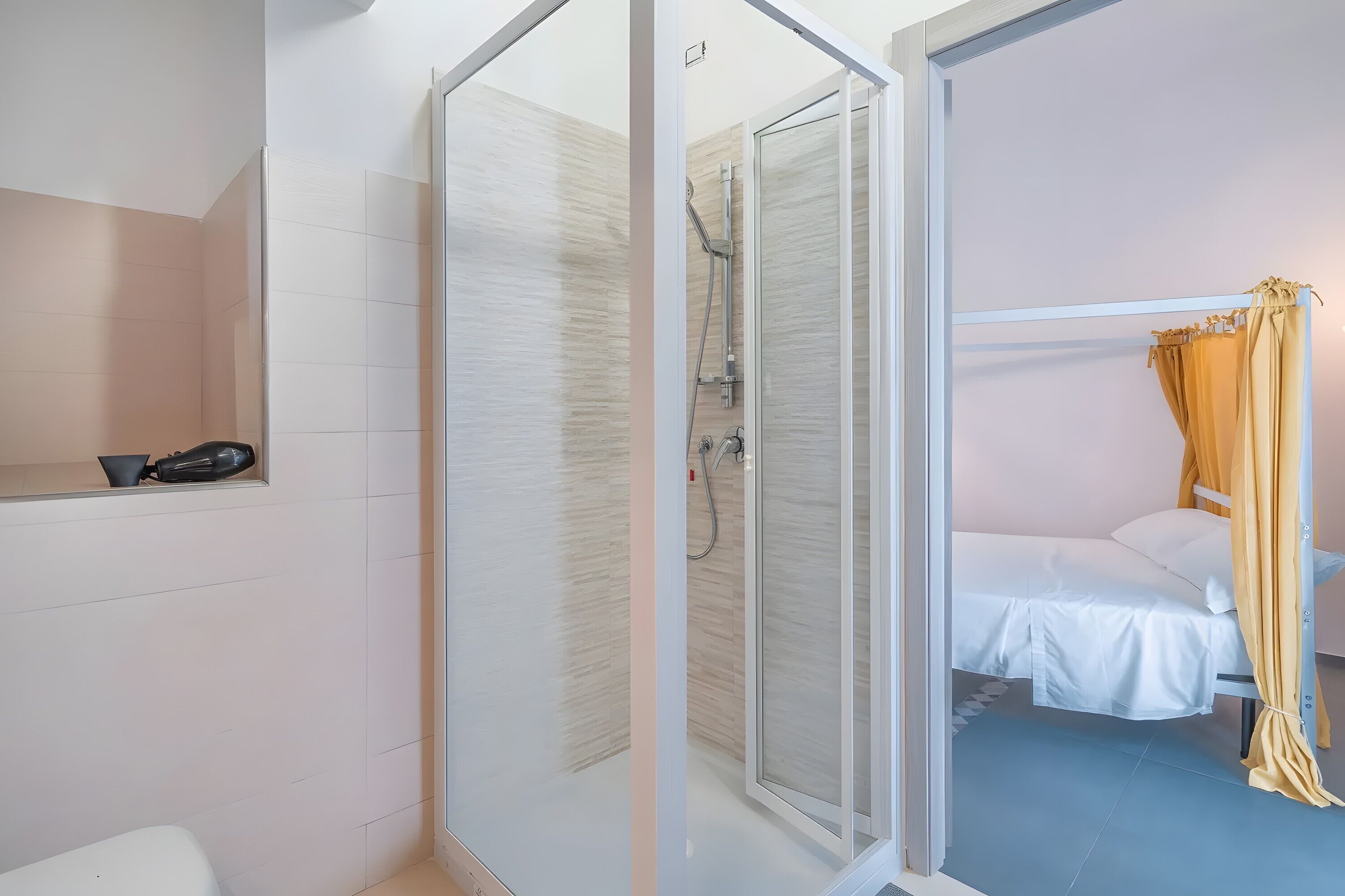 A bathroom with a shower, toilet, and a small shelf with a hairdryer.
