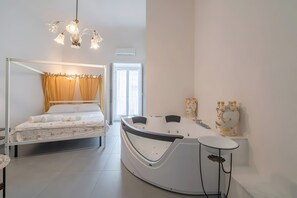 A modern bedroom with a four-poster bed, a curved bathtub, and a white sink.