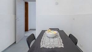 A dining area with a table, chairs, a bowl with flowers, and a door leading to another room. - Room 'Al 214 - Triple' with Wi-Fi and Air Conditioning (Ragusa)