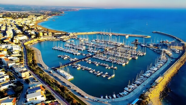 An aerial view of a marina with numerous boats docked, surrounded by residential buildings and a curved road. - Room 'Al 214 - Triple' with Wi-Fi and Air Conditioning (Ragusa)