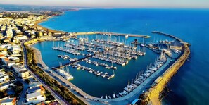 An aerial view of a marina with numerous boats docked, surrounded by residential buildings and a curved road.