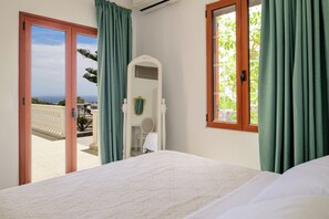 Une chambre à coucher avec un lit, un miroir, une chaise et une vue sur l’extérieur.