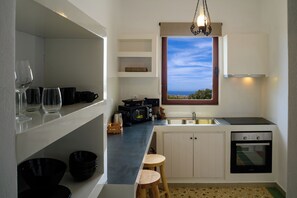 Une cuisine de taille réduite, dotée d’une fenêtre, d’un four à micro-ondes, d’un évier et d’un lave-vaisselle.