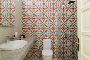 A bathroom with a patterned tile wall, a white sink, and a toilet.