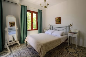 A bedroom with a bed, a bedside table, a mirror, and a window with curtains.
