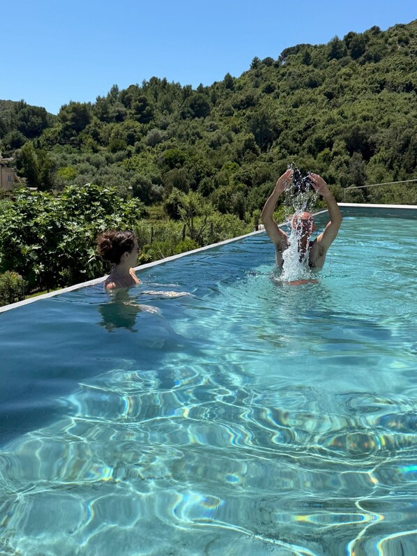 Une piscine à l’eau claire, offrant une vue sur une colline boisée.