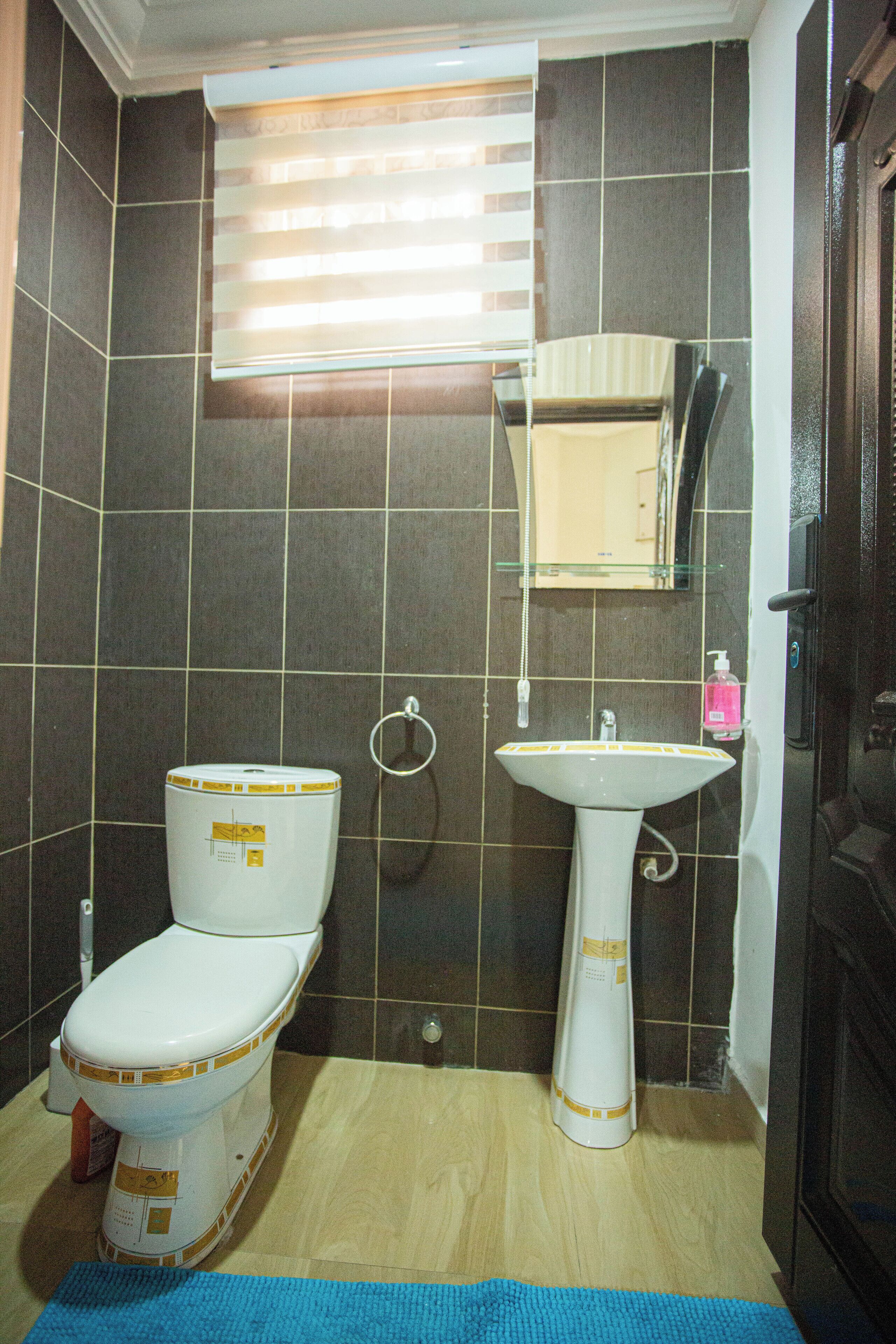 A bathroom with a toilet, sink, and mirror.