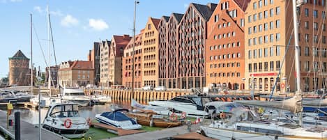 Ein Yachthafen mit verschiedenen Booten an den Stegen, umgeben von Gebäuden unterschiedlicher Architektur.