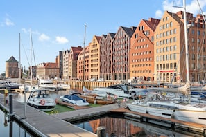 A marina with various boats docked, surrounded by buildings with distinct architectural styles. - GRANO APARTMENTS Gdańsk Granaria (Gdańsk)