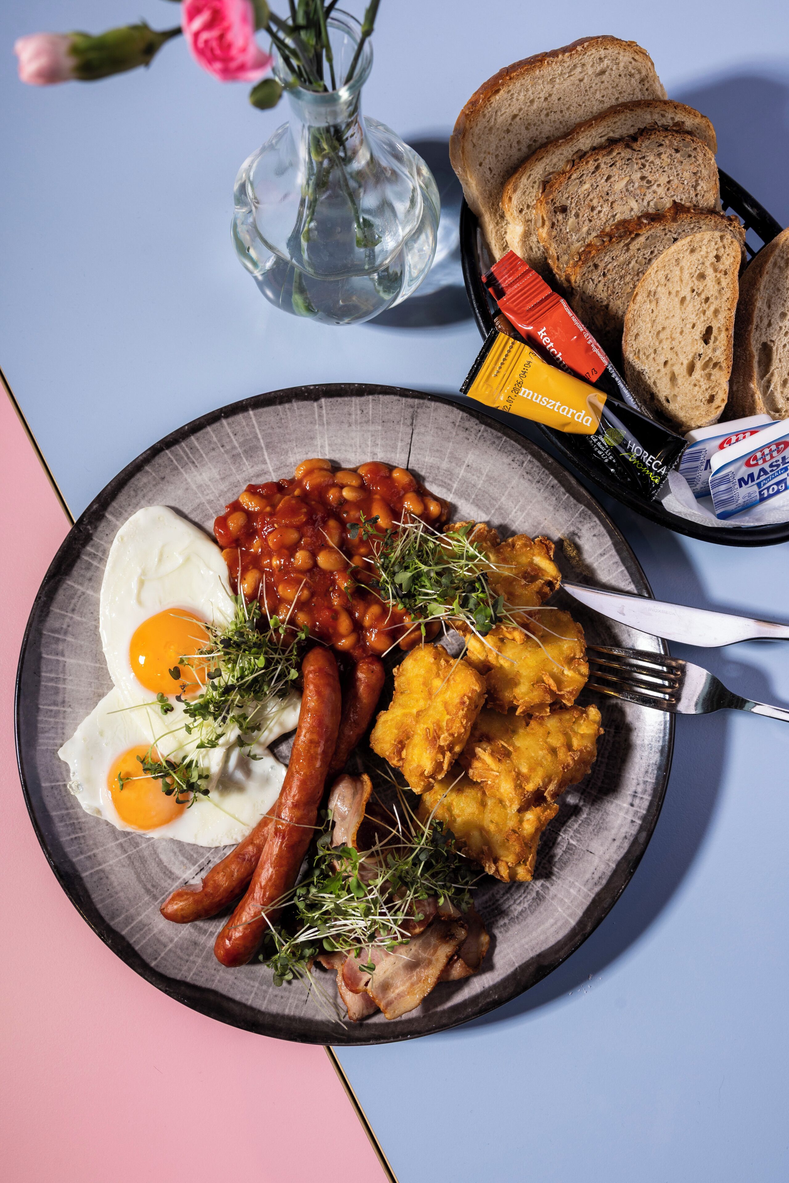 A breakfast plate with eggs, sausages, beans, and hash browns.