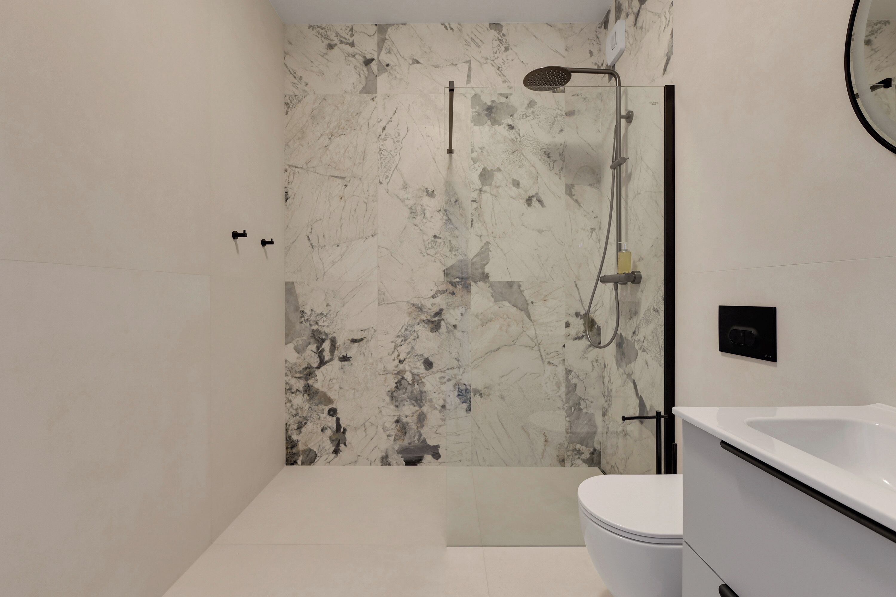 Un baño moderno con una bañera blanca, una ducha con cabezal de ducha de mano y un inodoro.