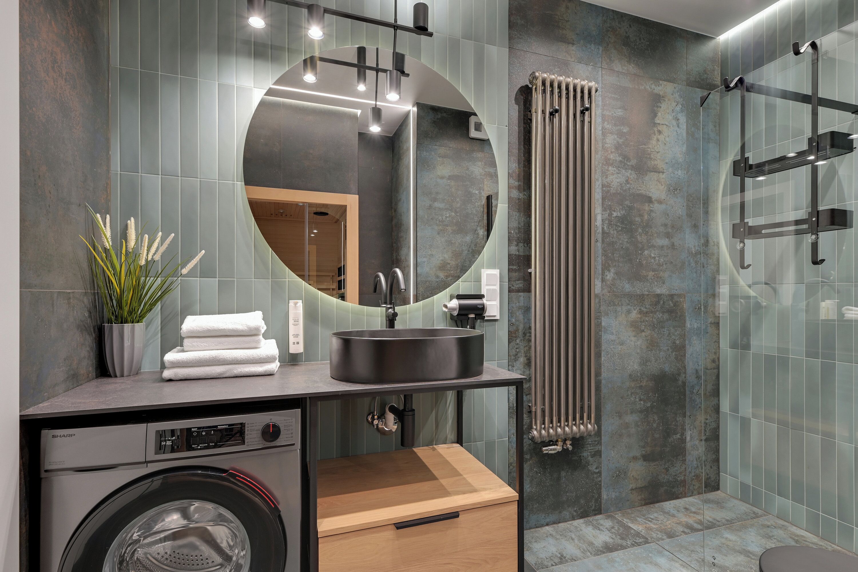 Ein modernes Badezimmer mit integrierter Waschmaschine, einem Waschbecken mit Spiegel und einem Handtuchhalter.