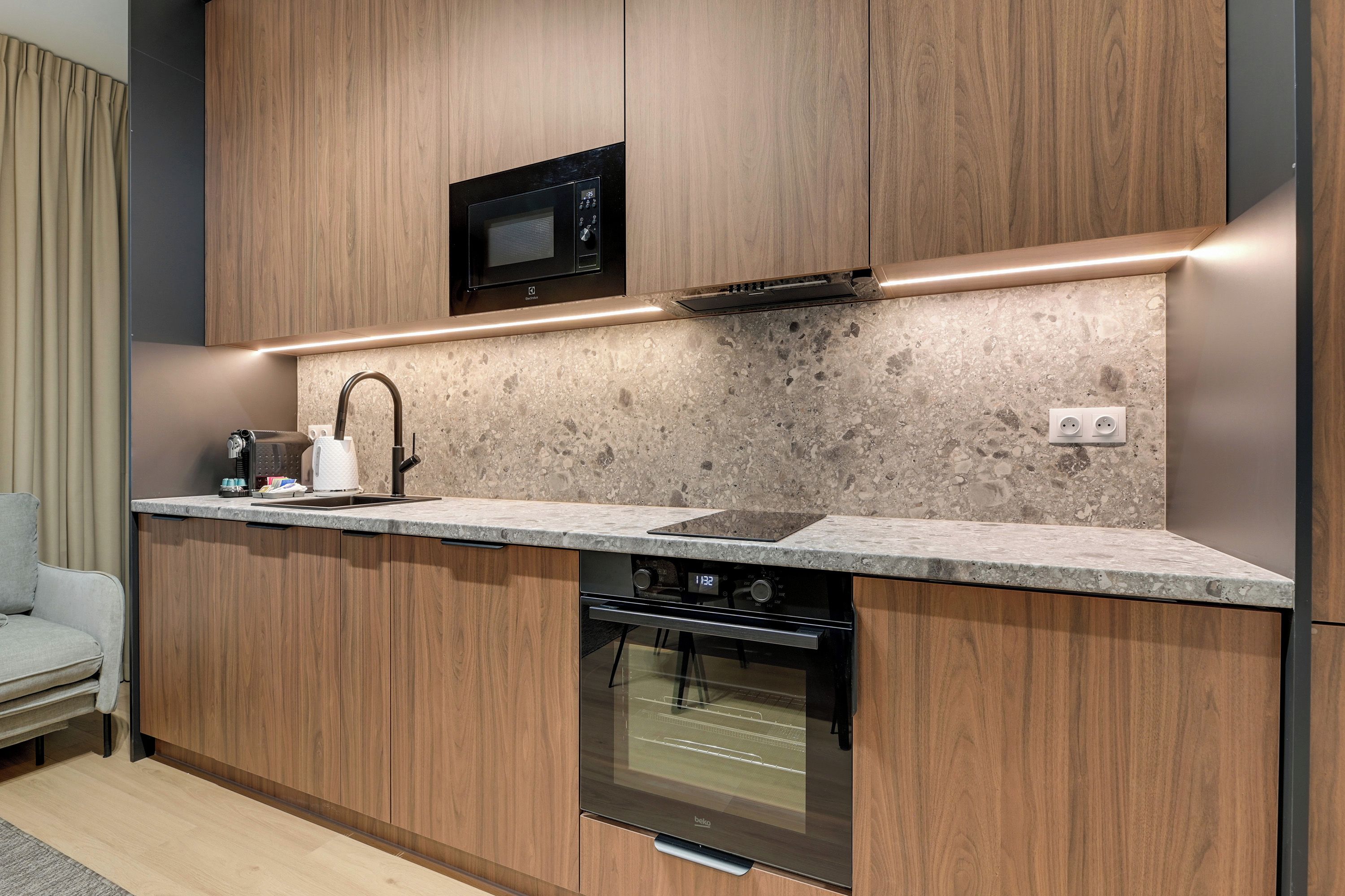 Een moderne keuken met houten kastjes, een ingebouwde magnetron, een roestvrijstalen oven en een granieten aanrecht.