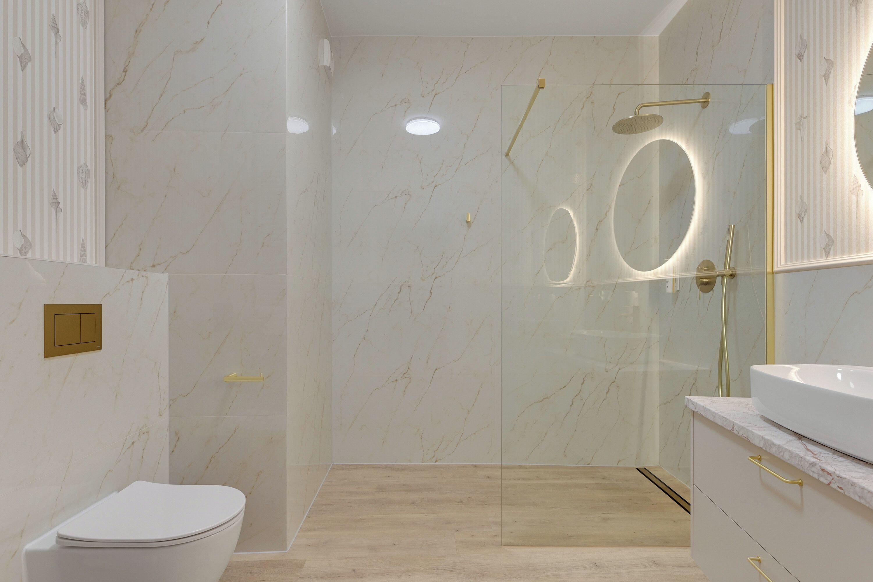 Un baño moderno con inodoro, ducha envuelta en vidrio con cabezal dorado y tocador con lavamanos blanco y pomos dorados.