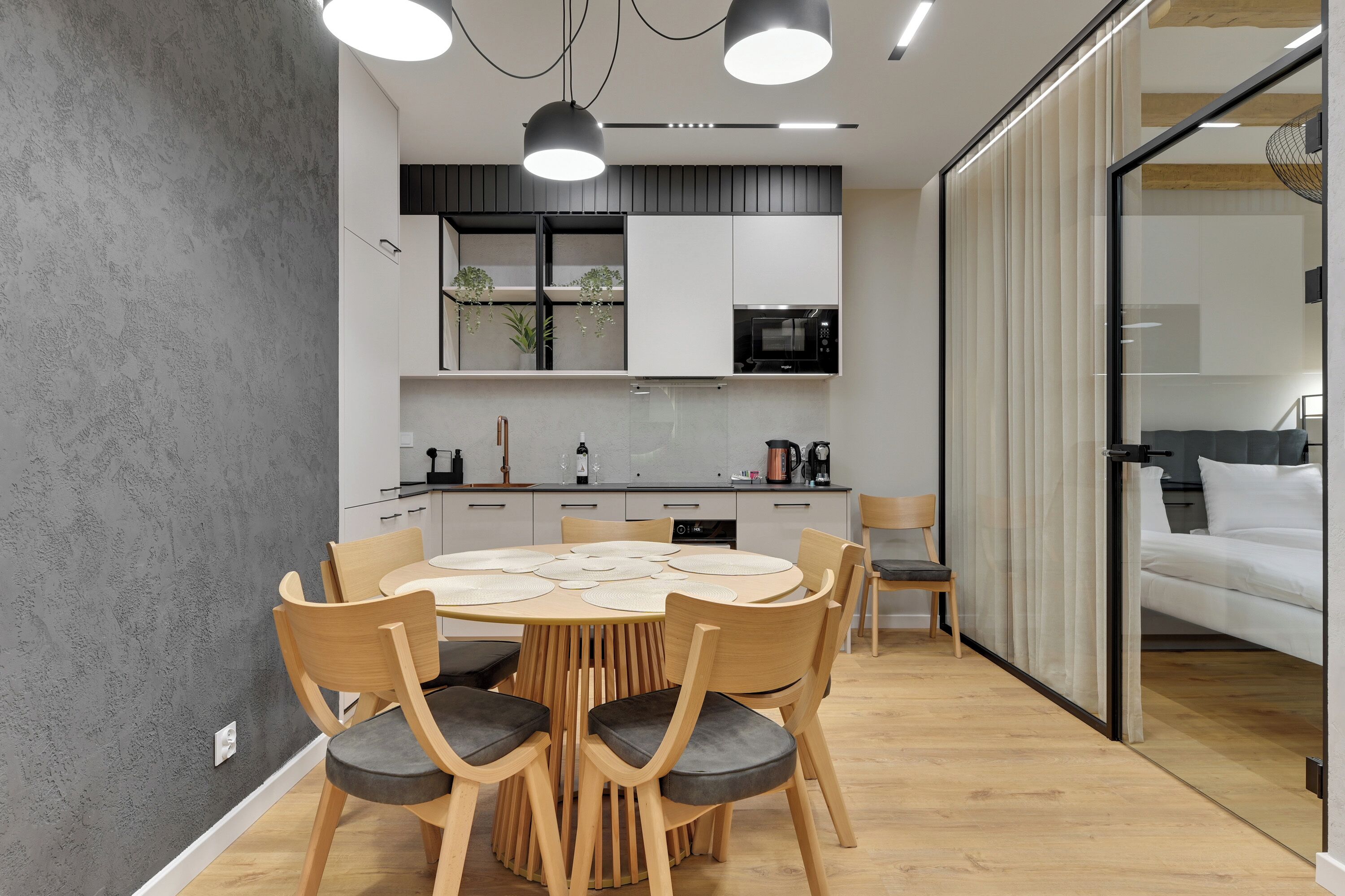 Una cocina moderna con una mesa redonda, sillas de madera y electrodomésticos integrados.