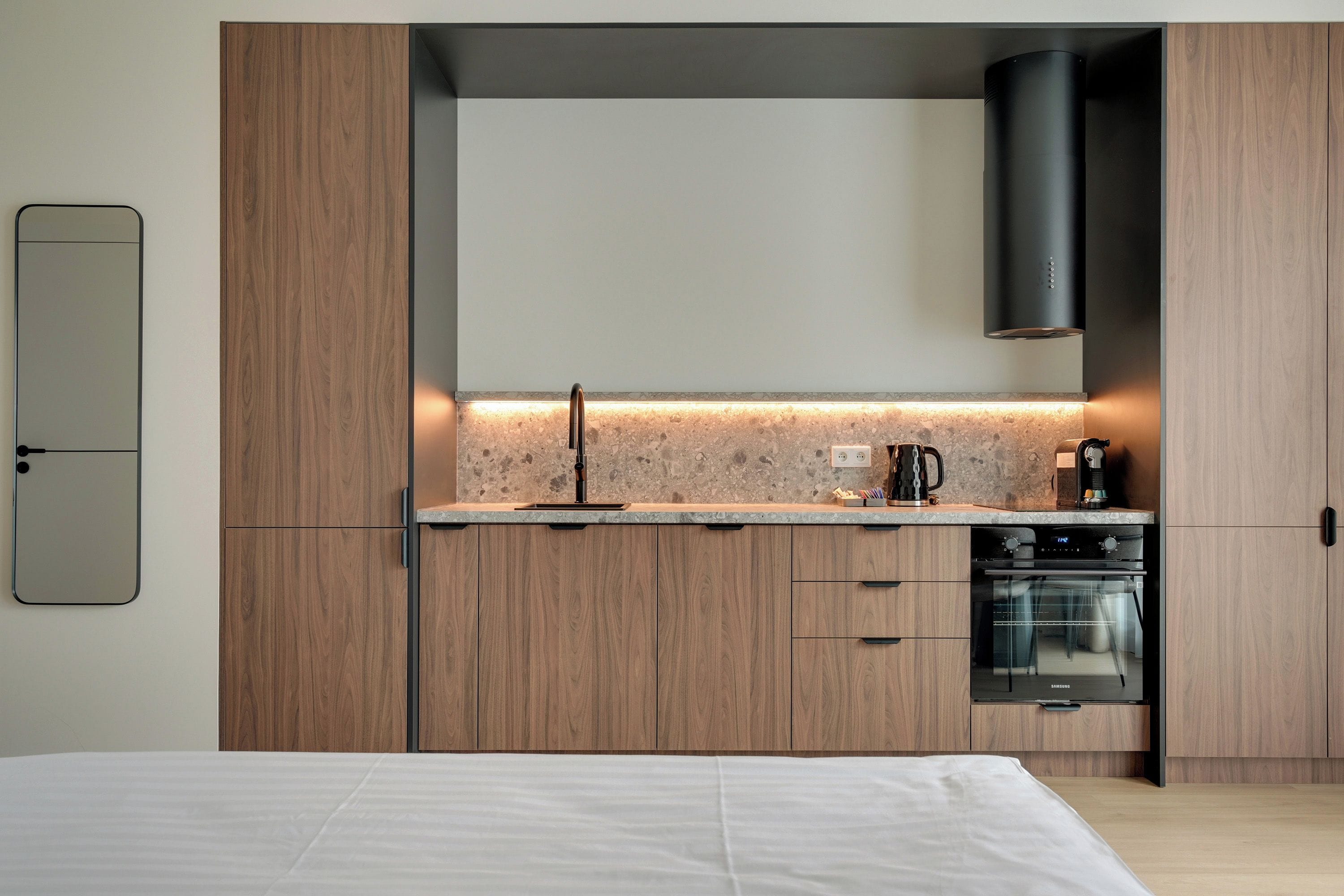 A modern kitchen with wooden cabinets, a built-in oven, and a countertop with a backsplash.