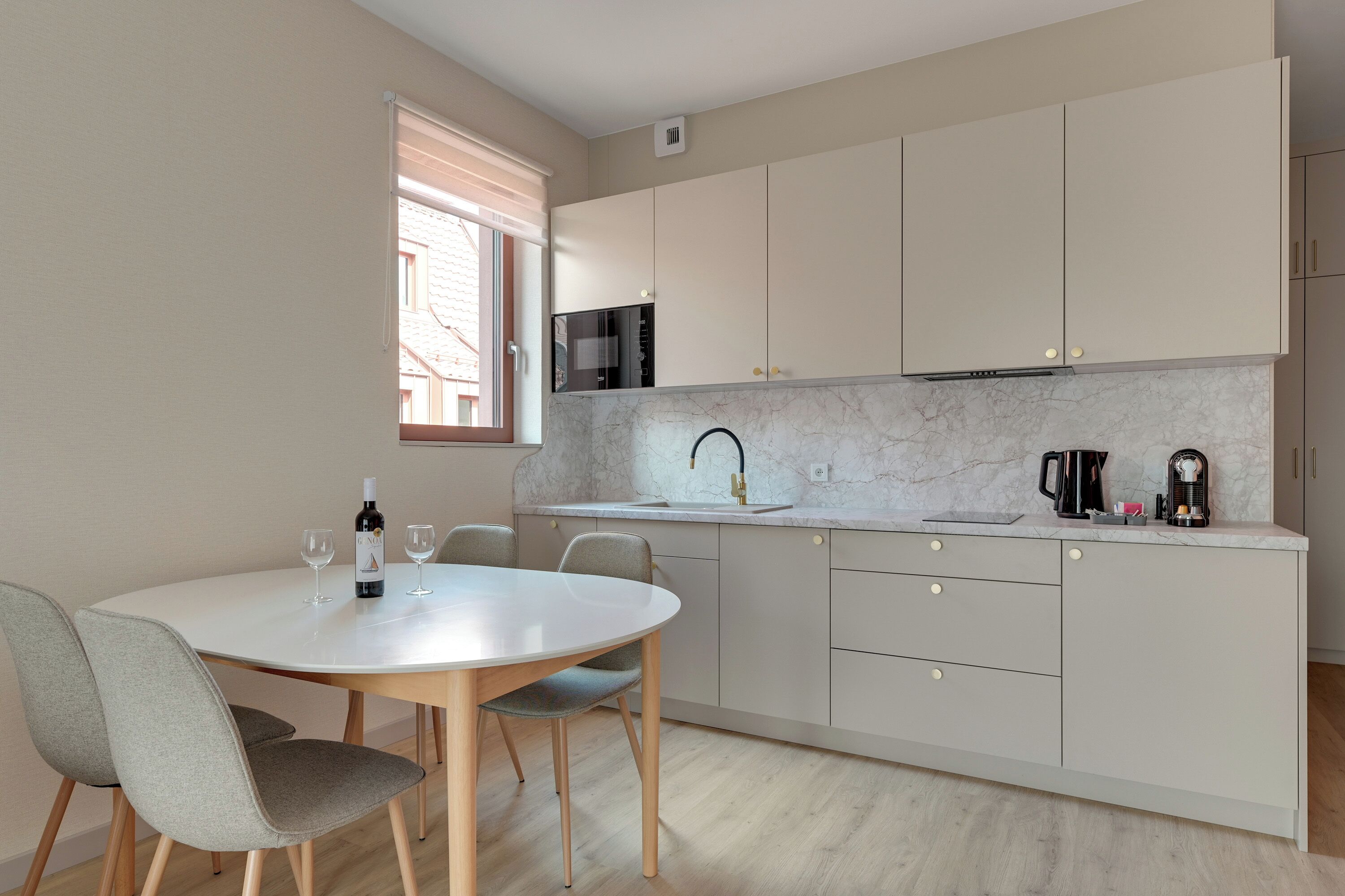 A modern kitchen with a white countertop, grey cabinets, and a round dining table with chairs.