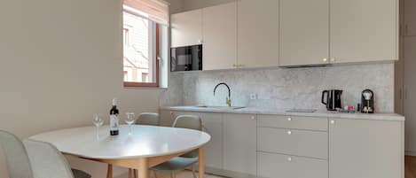 A modern kitchen with a white countertop, grey cabinets, and a round dining table with chairs.