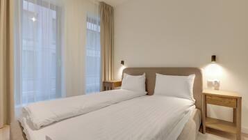 Habitación de hotel con una cama grande, dos mesitas de noche y una lámpara de pared.